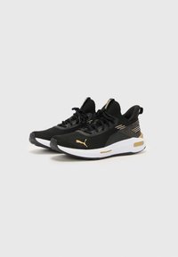 Baskets de sport noires avec tige en mesh, accents dorés et semelle extérieure blanche. Présente un design à lacets et une semelle intermédiaire rembourrée pour le soutien.