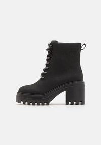 Czarny botek za kostkę na wysokim, masywnym obcasie z teksturowaną gumową podeszwą. Posiada sznurowadła oraz logo po boku. Wykonany z miękkiego materiału.