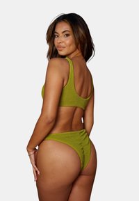 Olivgrön stickad bikini med en texturerad finish, med en scoop-back topp och rynkade hög midja underdel, visad från en sidovinkel.