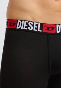 Czarne bokserki z szerokim elastycznym pasem z logo "DIESEL" w kolorze białym i czerwonym. Gładka tekstura i dopasowany kształt.