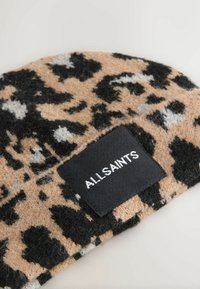 Leopard-print beanie in beige with black and gray spots. Textured wool material with a black label featuring white "ALLSAINTS" lettering.
