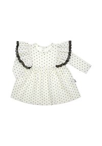Biała sukienka w czarne groszki z długim rękawem, posiada szerokie falbaniaste ramiona z czarną koronkową lamówką, rozkloszowany krój spódnicy.
