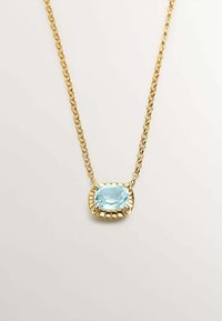 Collar de cadena de oro que presenta una gran piedra preciosa azul claro de corte cojín, engastada en un bisel texturizado y ornamentado. Diseño simple y elegante.