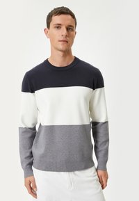 Maglione da uomo con collo rotondo, caratterizzato da righe orizzontali in blu navy, bianco e sfumature di grigio. Realizzato in un materiale morbido e liscio.