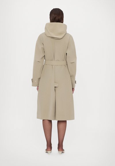 Beżowy trencz z kapturem, paskiem w talii i długimi rękawami. Posiada długość do kolan i gładką teksturę.