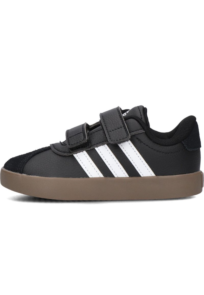 Černé tenisky s bílým designem tří pruhů, se semišovou špičkou a nastavitelnými suchými zipy, umístěné na hnědé gumové podrážce.