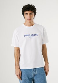 White cotton t-shirt featuring blue "PEPE JEANS LONDON" text, round neckline, and short sleeves, paired with light blue denim jeans.