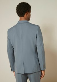 Hellgraue Anzugjacke mit Reverskragen, einer Schlitzöffnung hinten und geknöpften Manschetten. Glatte Textur und taillierter Schnitt.