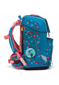 Sac à dos bleu avec des accents roses, présentant un motif à pois, un rembourrage en maille sur les bretelles et un design de patch circulaire sur le côté.