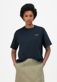 Námorně modré bavlněné tričko s krátkým rukávem a kulatým výstřihem. Na hrudi má malé bílé logo "Barbour". Hladká textura.