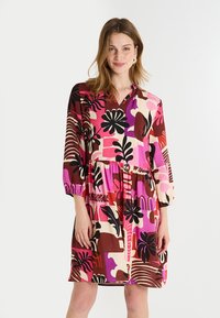 Vestido de algodón multicolor con escote en V, mangas de tres cuartos y un diseño en capas. Presenta patrones atrevidos en tonos de rosa, marrón y negro.