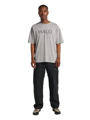 Mand stående iført en grå HALO-logo T-shirt, sorte cargobukser og beige sportssko mod en hvid baggrund.