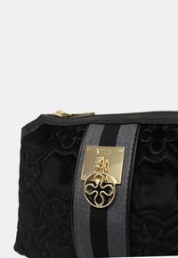 Borsa cosmetica in velluto nero con placca logo dorata, chiusura con cerniera e accenti a strisce grigie. Motivo floreale impresso sul tessuto.