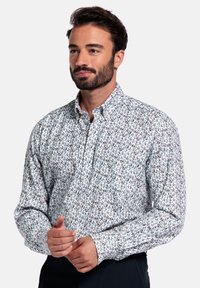 Langermige blouse in lichtblauw met een bloemenpatroon in bruin en groen, gemaakt van zachte katoen stof.