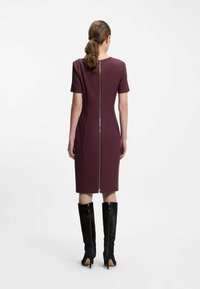 Mekko, jossa on lyhyt hiha ja takana keskellä vetoketju, väriltään mauve. Yhdistetty polveen ulottuviin mustiin korkokengissä. Sileä pinta.