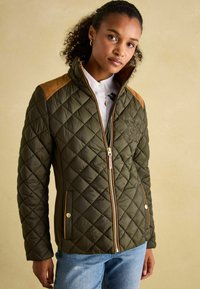 Jakna od patchworka u maslinasto zelenoj boji s smešnim naglascima na ramenima, zlatnim patentnim zatvaračem i dugmadi džepovima. Ima visok kragna i izvezenu oznaku.