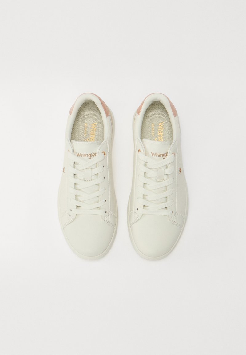 Zapatillas deportivas de cuero blanco con un acabado suave, con detalles en rosa claro, punta redonda y cordones blancos. Logo dorado en la planta. Suelas ligeramente texturizadas.