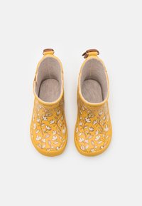 Botas de lluvia amarillas para el tobillo con un patrón floral, detalles en color beige, suelas texturizadas y un acabado liso y brillante. Parte superior abierta para facilitar su uso.