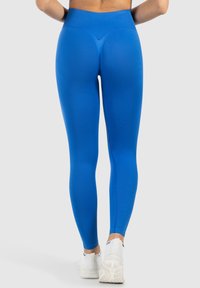 Leggings bleu taille haute en tissu lisse et extensible, dotés d'un design sans couture et d'une coupe ajustée le long des jambes jusqu'aux chevilles.