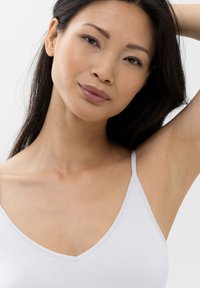 Witte camisole met dunne bandjes, V-hals ontwerp, rekbare stof, gladde textuur, met minimale naden voor een naadloze uitstraling.