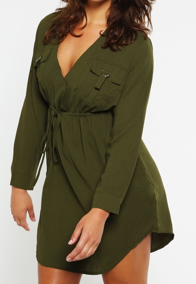 Femme portant une robe ajustée olive à manches longues avec des poches avant, une ceinture à la taille et un décolleté en V profond.