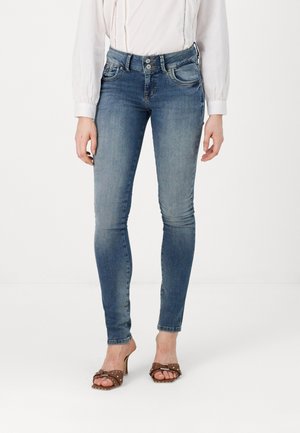 Skinny blue denim jeans with a faded wash, two front pockets, and a high waist, paired with brown heeled sandals featuring a buckle detail.