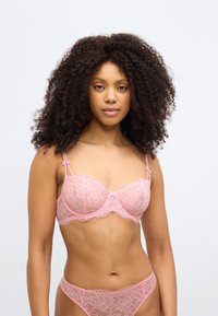 Ροζ δαντελένιο σουτιέν και αντίστοιχο σλιπ, με λουλουδάτο σχέδιο, διαφανές υλικό, ρυθμιζόμενες τιράντες, με κυματιστά πλαϊνά και μικρά φιόγκους ως διακοσμητικά.