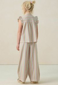 Striped two-piece outfit in pastel colors, featuring a ruffle-sleeve top and wide-leg pants, made of lightweight fabric with a soft texture.