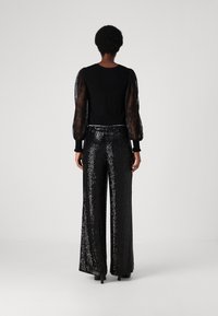 Black long-sleeve top with sheer puffed sleeves paired with wide-leg sequin trousers, both featuring a fitted silhouette and smooth texture.