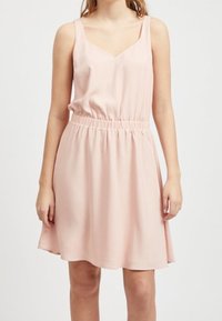 Różowa sukienka bez rękawów z dekoltem w kształcie V, zebranym w pasie i lekko teksturowanym materiałem, który sięga do kolan. Prosty, luźny krój.