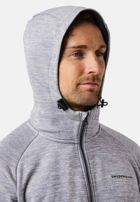 Grau zip-up Kapuzenpullover aus strukturiertem Stoff, mit verstellbaren Kordeln an der Kapuze und einem hohen Kragen. Mit dezentem Branding auf der Brust.