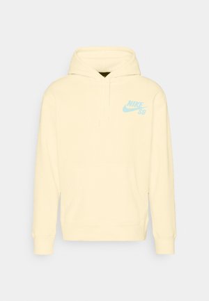 Jasnożółta bluza z kapturem, z przednią kieszenią i małym niebieskim logo Nike SB na lewej piersi.