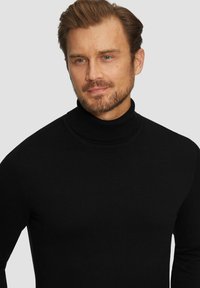 Czarny sweter typu golf w miękkim dzianinie, z wysokim karczkiem i dopasowanym krojem, bezszwowym wzorem na ramionach i minimalnymi detalami.