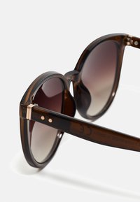 Tortoiseshell solbriller med gradient linser, rund form, metal accent ved hængslerne, og gravering på den indre arm.