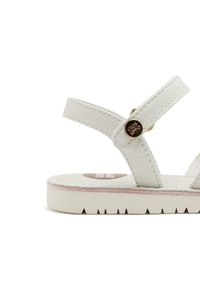 Sandalia de cuero blanco con tiras finas, detalle de logo redondo y suela de goma texturizada con patrones cortados.