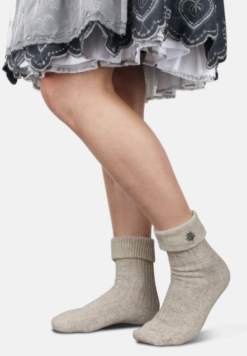 Beige gerippte Socken mit umgeschlagenem Bündchen und einem Stern-Detail. Strukturiertes Gewebe mit dezenten Farbvariationen. Getragen mit einem gestuften grauen Rock.
