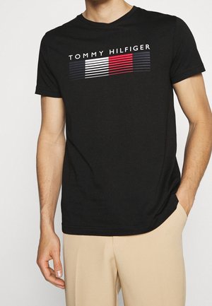Black cotton T-shirt featuring a horizontal logo design in white, red, and navy blue stripes. Short sleeves and a crew neck.