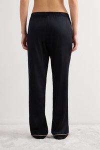 Pantalones negros de tipo satinado con cintura elástica, piernas rectas y un sutil ribete color tostado en el dobladillo. Textura suave, diseño minimalista.