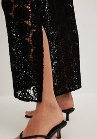 Sort blonderet beklædning med blomsterprint og en sidelommer. Båret med sorte hælede sandaler med åben tå.