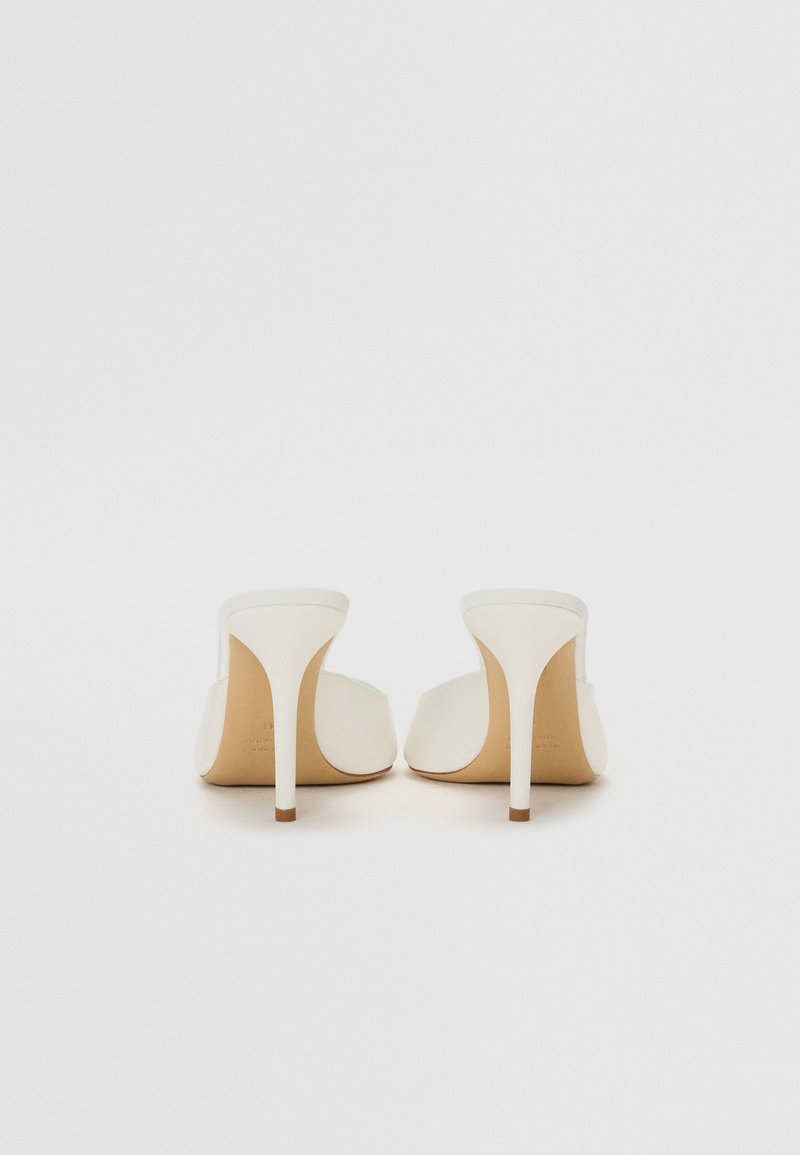 Hvide hæl mules med åben tå-design, glat læderoverdel og slank hæl. Neutral tone med en mat finish.