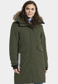 Groene parka met een met bont gevoerde capuchon, voorzakken en verstelbare manchetten; heeft een gladde textuur en een ritsluiting.