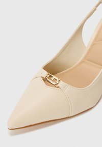 Décolleté beige con punta affilata, in pelle liscia, con un dettaglio in metallo dorato sul collo del piede. Suola flessibile per il massimo comfort.