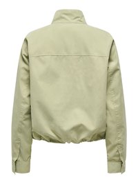 Veste beige clair à manches longues avec col montant, taille et poignets élastiqués, vue de dos sur fond blanc.