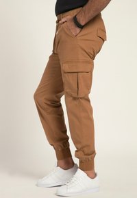 Cargo-Jogginghose in Tan. Hergestellt aus leichtem Stoff, mit elastischen Bündchen, Seitentaschen und Kordelzugbund für eine verstellbare Passform.