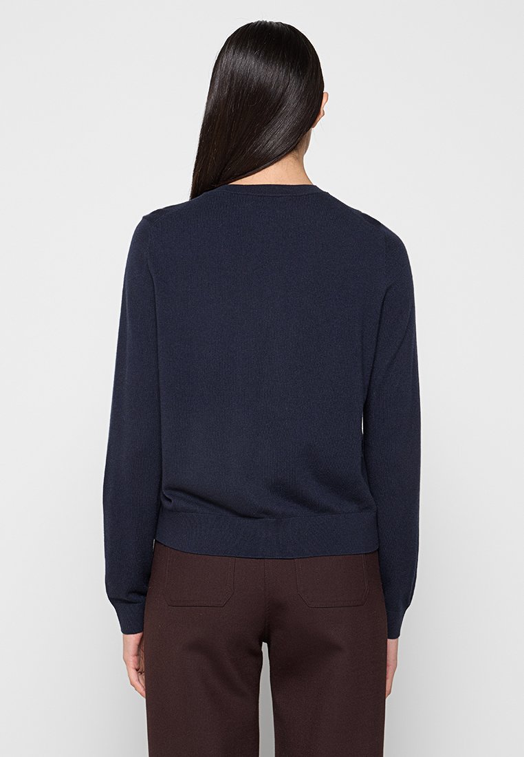 Marineblauer Strickpullover mit langen Ärmeln und rundem Ausschnitt. Gerippter Saum und Bündchen. Glatte Textur, keine sichtbaren Muster oder Akzente.