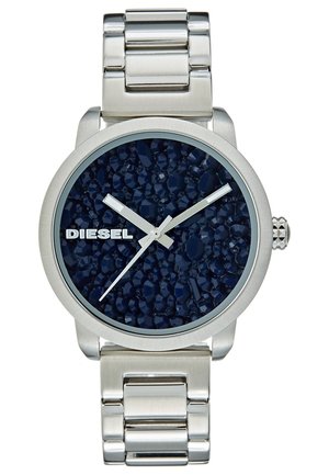 Montre-bracelet Diesel argentée avec cadran bleu foncé texturé, trois aiguilles argentées et bracelet en maillons métalliques.