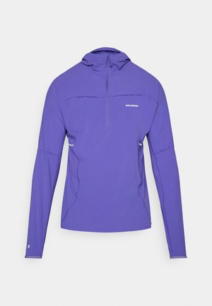 Pull-over violet à manches longues avec un col zippé mi-hauteur, fabriqué en matière légère, doté de coutures plates et d'accents réfléchissants.