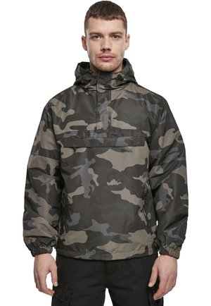 Anorak con patrón de camuflaje en tonos de verde y gris, con capucha ajustable, bolsillos laterales con cremallera y puños elásticos. Material impermeable.