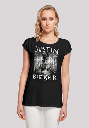 Black t-shirt featuring a central image of a male figure with tattoos, overlaid with the text "JUSTIN BIEBER" in bold white letters.