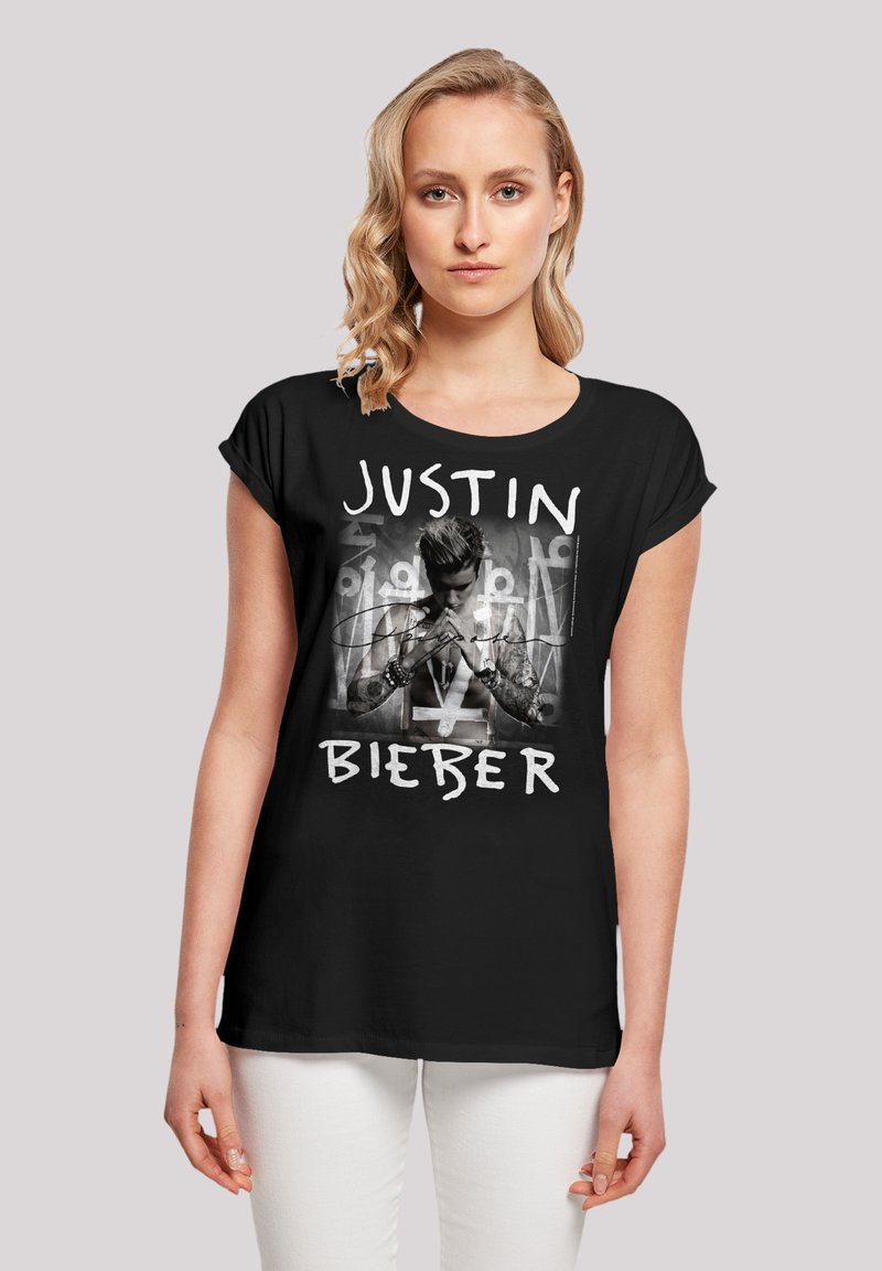 Black t-shirt featuring a central image of a male figure with tattoos, overlaid with the text "JUSTIN BIEBER" in bold white letters.